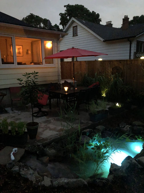 Random flagstone patio and a fish pond at night. Stone or paver patio project in London Ontario region by O'Connor Stone & Landscape, local landscape and hardscape contractor.