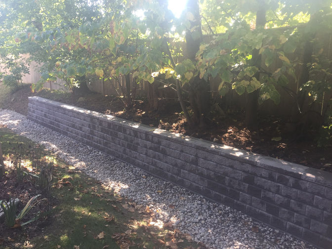 Engineered retaining wall with dry river bed. A retaining wall cladding project by the London Ontario based O'Connor Stone & Landscape